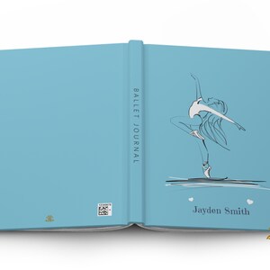 May include: A light blue journal with a black line art illustration of a ballet dancer on the front cover. The spine reads BALLET JOURNAL. The name Jayden Smith is printed below the dancer with two small white hearts. A QR code is on the back.