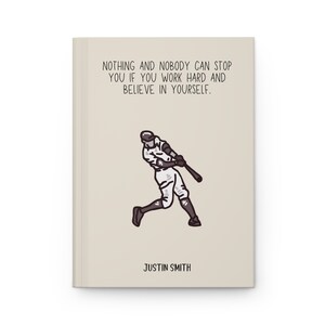 May include: A beige notebook with the text "NOTHING AND NOBODY CAN STOP YOU IF YOU WORK HARD AND BELIEVE IN YOURSELF." and a baseball player illustration. The name "JUSTIN SMITH" is printed at the bottom.