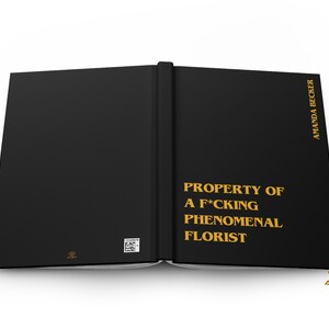 May include: A black hardcover book with gold lettering on the front cover that reads PROPERTY OF A F*CKING PHENOMENAL FLORIST and AMANDA BECKER. The back cover features a small square QR code and a small gold logo at the bottom center.