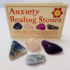 May include: A small bag of anxiety healing stones. The bag contains sodalite, rose quartz, amethyst, and blue calcite. The text on the card reads "Anxiety Healing Stones. This bag contains sodalite, rose quartz, amethyst, and blue calcite. For calming the mind, releasing tension. Attracts peace, tranquility and serenity. www.sacralshack.co.uk, find us on social media at 'sacral shack'."