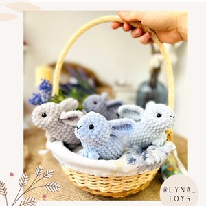 Puede incluir: Cuatro juguetes de conejo enano de crochet en una cesta de mimbre. Los conejos son azul claro y gris. La cesta est&aacute; forrada con una tela floral. El texto "@LYNA_TOYS" y "Autor - Natalia Sapunova" es visible en la imagen.
