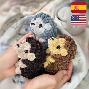 May include: Three crocheted hedgehog plushies in different colors: brown, blue, and tan. The plushies have small black eyes and are made with a fluffy yarn.