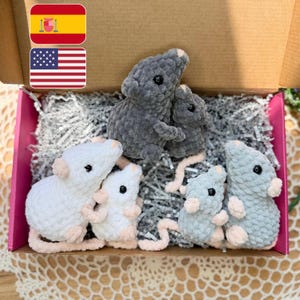 May include: A set of six crocheted plush mice in various sizes and colors, including dark gray, light gray, and white, with black plastic eyes and light pink accents on the ears and tails, nestled inside a cardboard box with shredded paper.