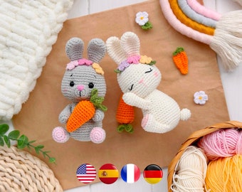 May include: Two crocheted stuffed rabbits, one gray and one cream, each wearing a floral crown. The gray rabbit holds an orange carrot, while the cream rabbit lies down next to another orange carrot. Small crocheted flowers and a carrot are nearby.
