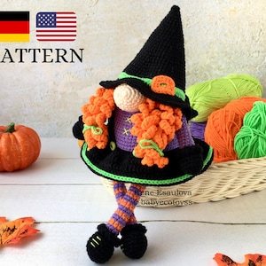 Può includere: Gnomo strega di Halloween all'uncinetto con capelli arancioni, vestito viola, cappello nero e gambe a strisce verdi e arancioni. Lo gnomo è seduto su una superficie di legno bianco con una zucca e foglie autunnali.