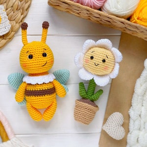 May include: A crocheted yellow bee with brown stripes and a white collar, and a crocheted white daisy with a yellow center and green stem in a brown pot.
