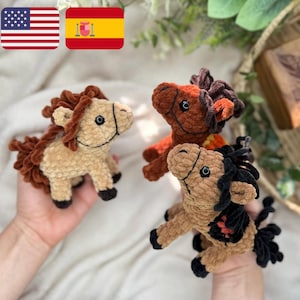 Puede incluir: Tres juguetes de peluche de caballo hechos a crochet. Uno es marrón con una crin marrón, otro es marrón con una crin negra y el último es marrón con una crin naranja.