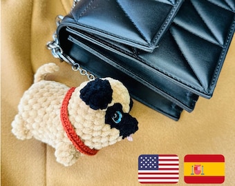 May include: A crocheted pug dog keychain with a red collar, attached to a black quilted handbag with a silver chain.