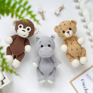Op de afbeelding: Drie handgemaakte gehaakte knuffels, waaronder een bruine aap met witte pootjes, een lichtgrijs nijlpaard en een beige luipaard met donkerbruine vlekken en witte pootjes. Elk dier is voorzien van zwarte veiligheidsoogjes en stiksels.