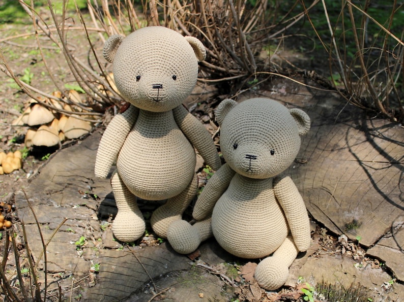 Peut inclure: Deux ours en peluche au crochet beiges sont pr&eacute;sent&eacute;s &agrave; l'ext&eacute;rieur. Les ours ont des yeux et des nez noirs et sont assis sur une souche d'arbre. Les ours sont faits d'un fil doux et textur&eacute; et ont une forme classique d'ours en peluche.