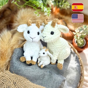 May include: Three crocheted goat figurines in a woven basket. The goats are white with tan horns and hooves. The basket rests on grey fabric, with greenery and a brown background. The smallest goat is a baby.