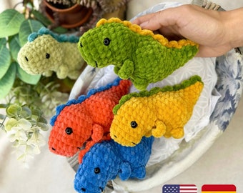 May include: Four crocheted dinosaur toys in a basket. The dinosaurs are green, orange, yellow, and blue.