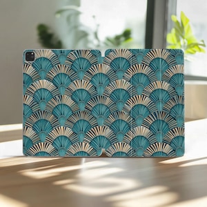 Könnte beinhalten: Eine Tablet-Hülle mit einem teal- und goldfarbenen Fächermuster. Das Design zeigt ein sich wiederholendes Muster aus stilisierten Fächerformen in Teal- und Goldtönen, wodurch ein strukturierter Art-Deco-Stil entsteht. Die Hülle ist geöffnet.