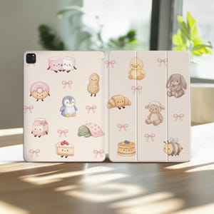 Puede incluir: Una funda para tableta de color beige claro con un patrón repetitivo de pequeños lazos rosas y varios personajes de dibujos animados, incluyendo malvaviscos, una dona, un pingüino, un cartón de leche, un trozo de pastel, un maní, una tortuga, un pato, un croissant, un conejo, un cordero y una abeja.