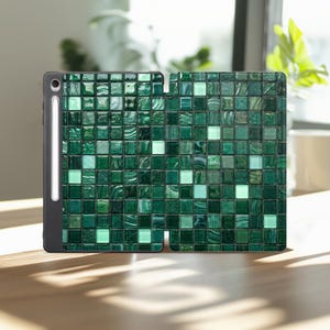 May include: A tablet case featuring a dark green mosaic tile pattern with varying shades of emerald, forest green, and light mint squares. The case has a black frame and includes a vertical slot on the left side holding a white stylus pen.