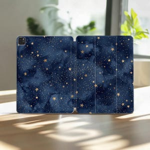 May include: A tablet case featuring a dark navy blue watercolor background with a pattern of scattered gold-colored stars and fine white speckles. The design covers the entire exterior surface, including the foldable front cover panels.