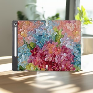 May include: A tablet case featuring a thick, textured impasto oil painting of a dense floral arrangement in shades of pink, magenta, blue, yellow, and white. The case includes a dedicated vertical slot on the left side holding a white stylus pen.