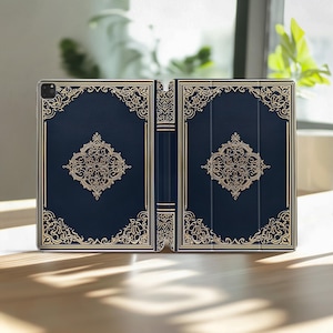 Peut inclure: Étui de tablette bleu marine avec un motif doré orné. L'étui est ouvert, révélant l'intérieur. Le motif présente des motifs floraux et de volutes complexes. L'étui est conçu pour ressembler à un livre vintage.