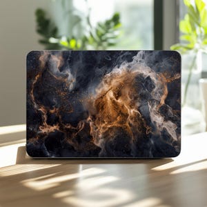 May include: A rectangular laptop skin featuring a dark, abstract design with swirling clouds of deep navy blue, charcoal gray, and warm copper-toned smoke. The surface is accented with fine, scattered gold-colored glitter particles throughout.
