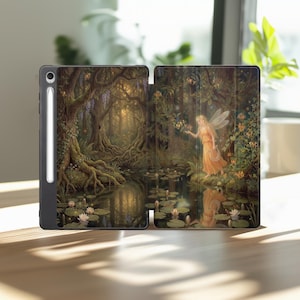 May include: A black tablet case featuring a detailed illustration of a fairy in a golden dress standing by a forest pond with lily pads and large trees. A white stylus is attached to the side of the case, which is open to display the artwork.