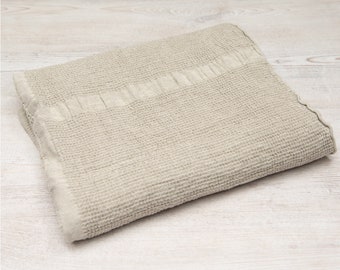 May include: A light gray waffle weave bath towel folded on a white wooden surface.