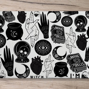 May include: Black and white illustration of a witchy pattern with various symbols, including eyes, hands, hearts, moons, cauldrons, and the words "Moon Spells" and "Witch".
