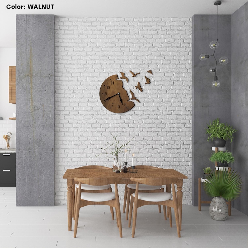 May include: A wooden wall clock with a unique design featuring birds flying out of the clock face. The clock is mounted on a white brick wall in a dining room setting with a wooden table and chairs.