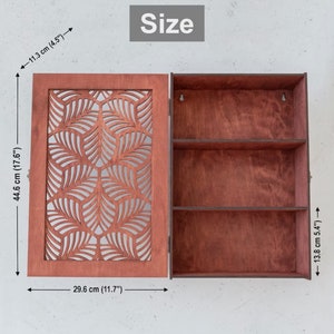 May include: A wooden wall cabinet with a decorative leaf pattern on the door. The cabinet has three shelves and measures 17.6 inches tall, 11.7 inches wide, and 5.4 inches deep.