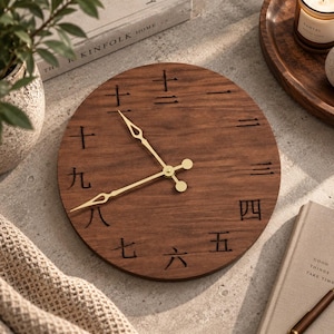 May include: A round wooden wall clock featuring a dark brown wood grain finish and gold-colored metal hands. The clock face displays traditional Chinese characters as numerals, arranged in a circular pattern to indicate the twelve hours of the day.