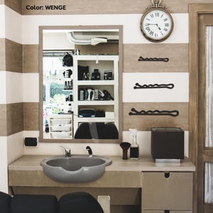 May include: A barber shop interior with a large mirror, a gray sink, and a wall clock. The walls are striped in white and brown. Three black bobby pins are mounted on the wall. The color of the interior is WENGE.