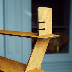 May include: A wooden shelf unit with three shelves. The shelves are made of light brown wood and have a natural finish. The unit is designed to be wall-mounted and has a modern, minimalist style.