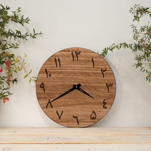 May include: A round wooden clock with Arabic numerals, a black hour and minute hand, and a brown wood grain finish.