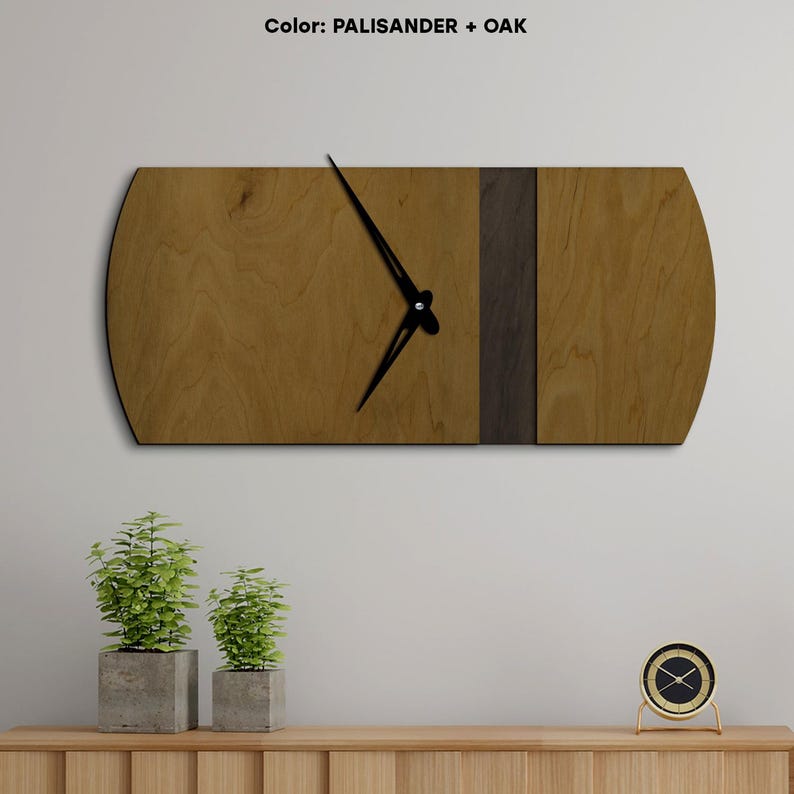 Op de afbeelding: Een houten wandklok met een zwarte wijzerplaat en wijzers. De klok is gemaakt van twee verschillende soorten hout, een lichtbruin en een donkerbruin. De klok is gemonteerd op een witte muur. De tekst "Color: PALISANDER + OAK" is zichtbaar bovenaan de afbeelding.