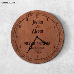 May include: A wooden clock with a brown alder finish. The clock face features a decorative floral design and the text "Jayden & Alyson Forever and Ever April 15th, 2024".