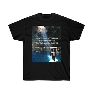 Puede incluir: Camiseta negra con un gráfico de un hombre con un monitor de computadora en la cabeza de pie en una cueva con un rayo de luz que brilla hacia abajo. El texto "SELF MONITORING advances to DIVINE ALIGNMENT" está impreso en la camiseta.