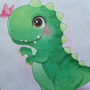 May include: A green cartoon dinosaur with a friendly expression and large brown eyes. A pink butterfly rests on its head. The dinosaur has a row of green spikes down its back and is set against a light background.