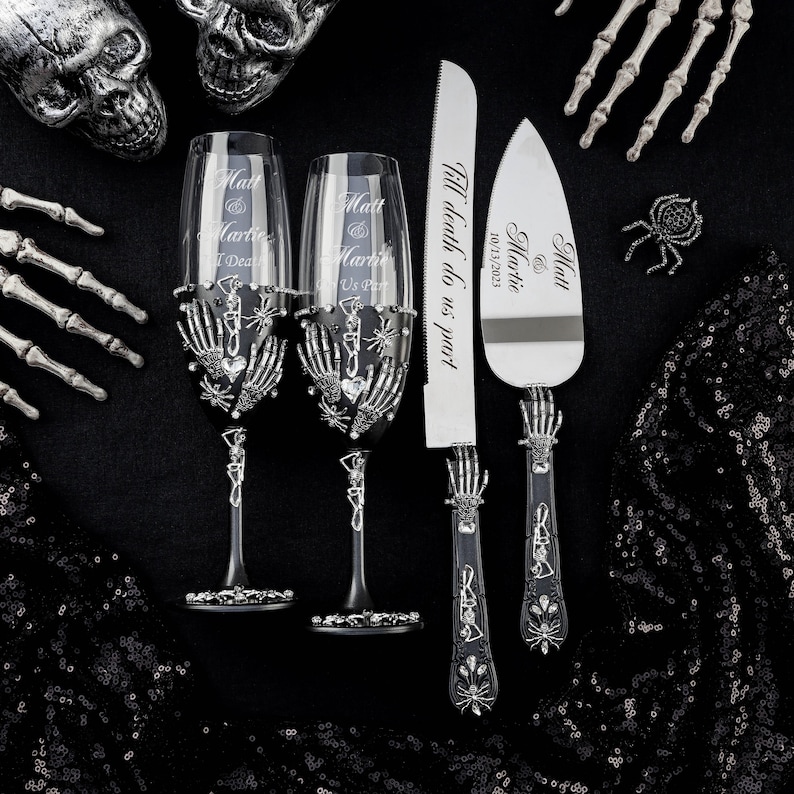 May include: A black and silver wedding cake knife and two champagne flutes with skeleton hands and spider details. The knife has the text "Till death do us part 10/13/2023 Matt & Martie" engraved on it.