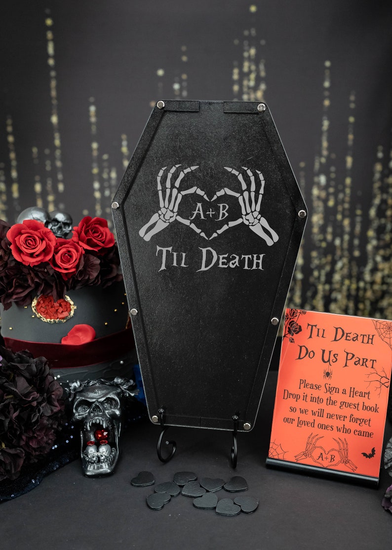 May include: Black coffin-shaped guest book alternative with the text "Til Death" and skeleton hands forming a heart. Includes a sign that says "Til Death Do Us Part". A gothic wedding theme.