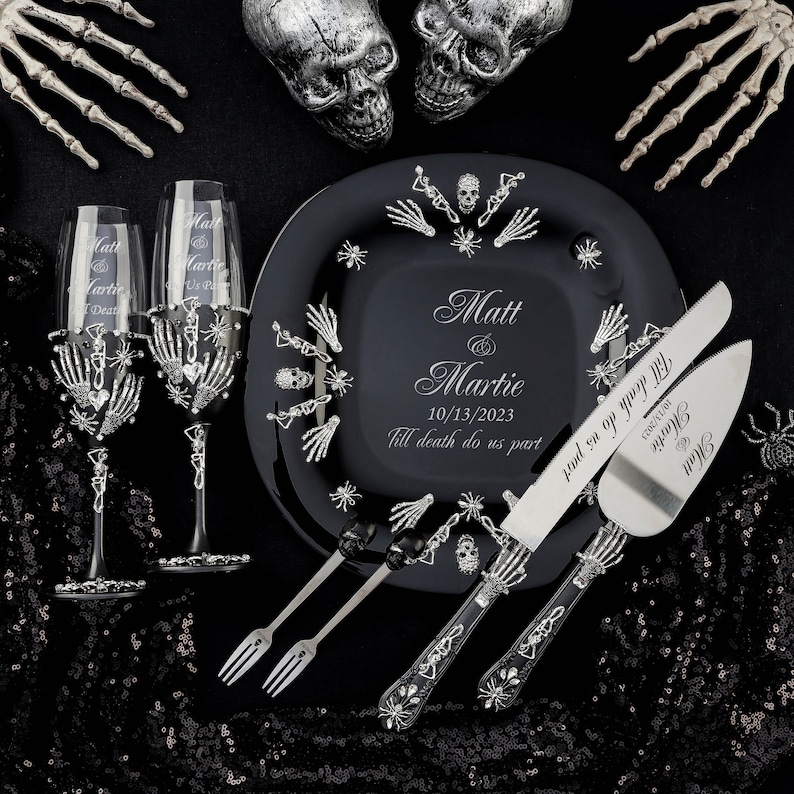 Op de afbeelding: Zwarte en zilveren taartserviesset voor bruiloften met een schedel- en kruisbeendesign. Het taartmes en de server hebben de tekst "Till death do us part" en de namen "Matt & Martie" met de datum "10/13/2023".