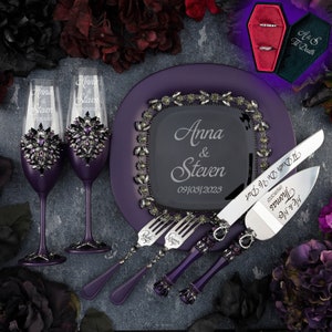 May include: Purple wedding cake serving set with a black and silver cake knife, two forks, and two champagne flutes. The knife and forks have purple handles with rhinestones. The champagne flutes are decorated with rhinestones and have the names "Anna & Steven" engraved on them. The cake plate is purple with a black square in the centre that says "Anna & Steven 09/03/2023".
