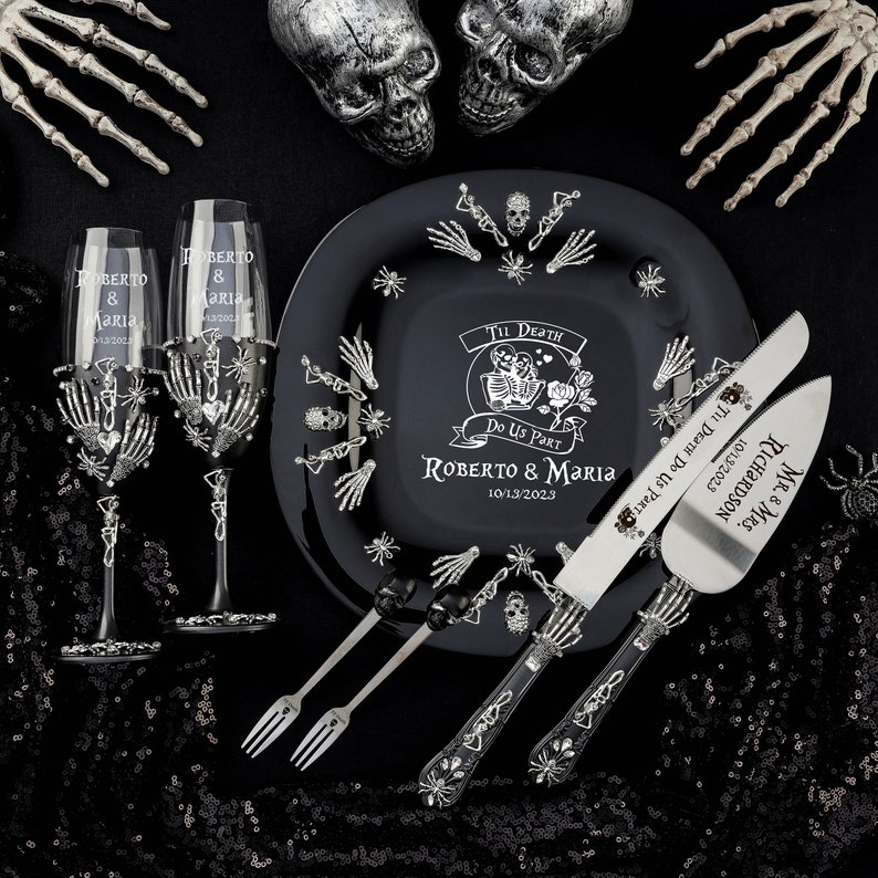 May include: A black wedding set with a skeleton theme. Includes two champagne flutes, a plate, cake server, and forks. The plate and server are engraved with names and a date. The flutes and server have skeleton hand details.