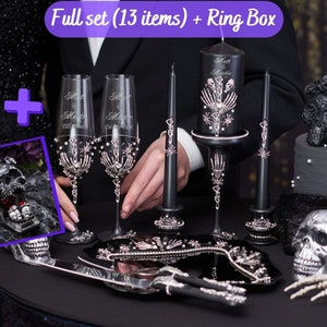 May include: A full set of gothic wedding decor, including champagne flutes, candles, and a ring box. The set features a black and silver color scheme with skeleton and skull motifs. The text on the champagne flutes reads "Matt & Martie Till Death Do Us Part."