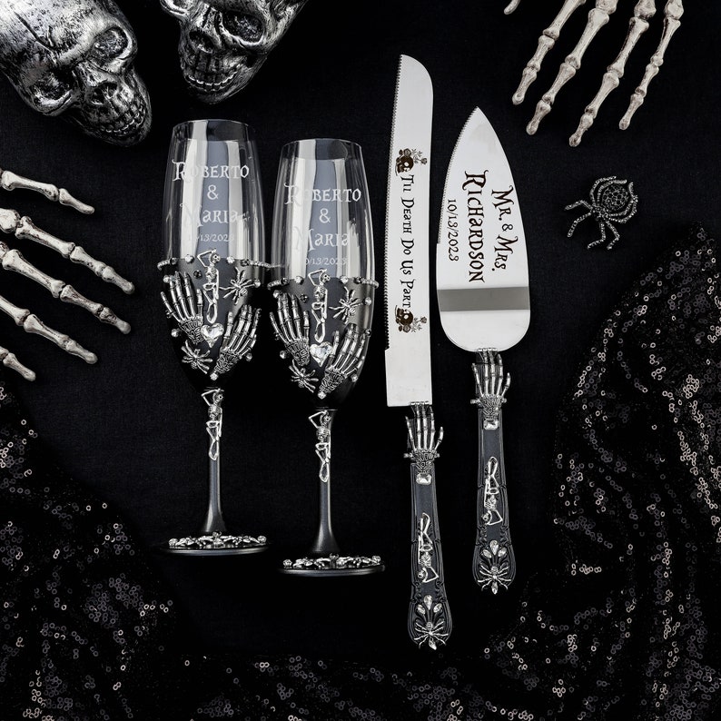 May include: A gothic-themed wedding set featuring two champagne flutes, a cake knife, and a server. The flutes and serving pieces have skeleton hand accents and are engraved with names and a date. The cake knife reads "Til Death Do Us Part".