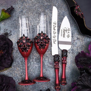 May include: Two red wine glasses with black rhinestone embellishments and the names "Anna & Steven" engraved on them. A red and black cake knife with the text "Mr. & Mrs. Thomas" and "Til Death Do Us Part" engraved on it.