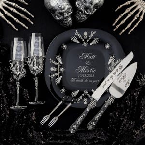 May include: Black and silver wedding cake serving set with a skull and crossbones design. The cake knife and server have the text "Till death do us part" and the date "10/13/2023". The set also includes two black and silver glasses with a skull and crossbones design.