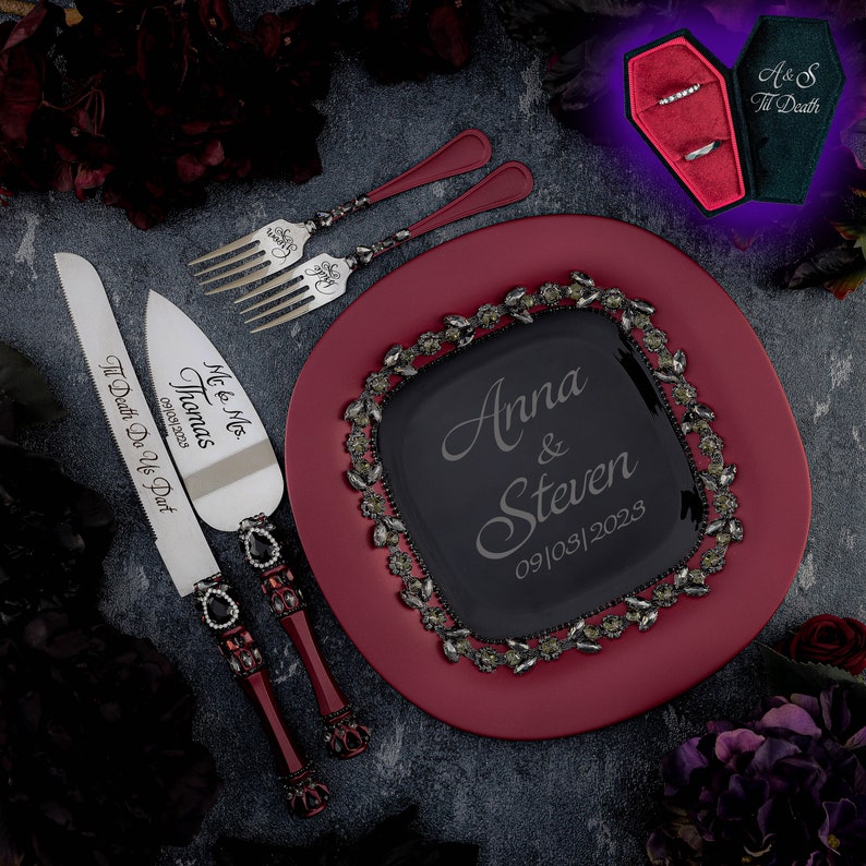 May include: A red and black wedding cake serving set with a knife and server. The knife has the inscription "Mc & Mrs. Thomas 09/09/2003 Til Death Do Us Part". The server has a black and red handle with a crown design. The cake plate is red with a black square in the center with the inscription "Anna & Steven 09/03/2023".