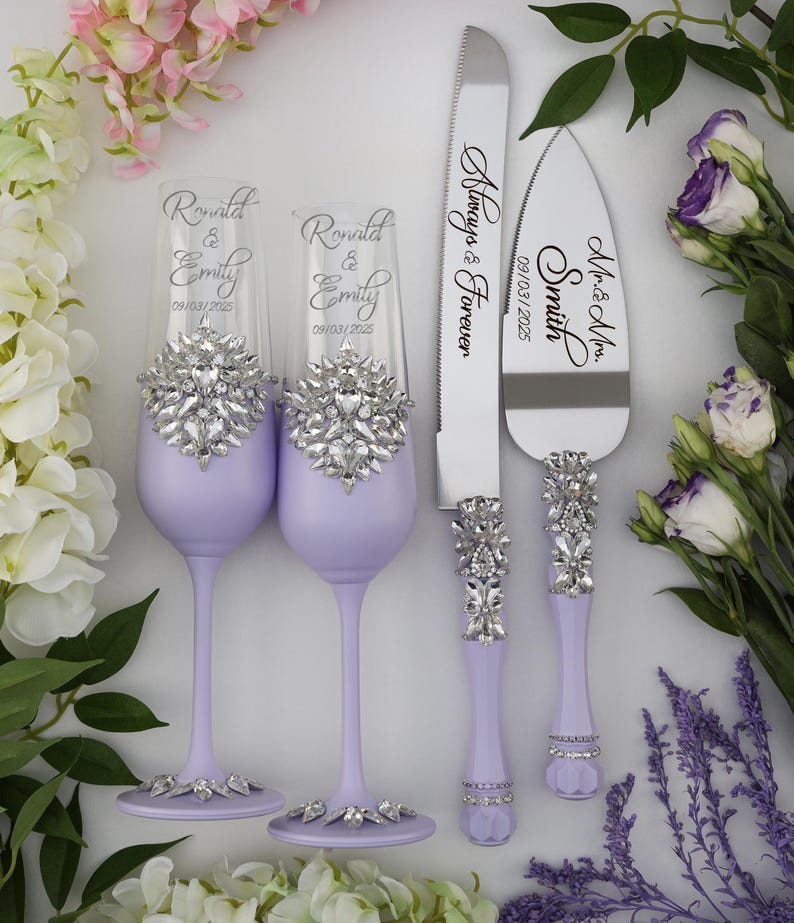 May include: A wedding set with two lavender colored champagne flutes and a cake knife and server. The flutes and handles of the knife and server are decorated with rhinestones. The flutes are engraved with the names "Ronald & Emily" and the date "09/03/2025". The knife is engraved with "Mr. & Mrs. Smith" and the server is engraved with "Always & Forever" and the date "09/03/2025".