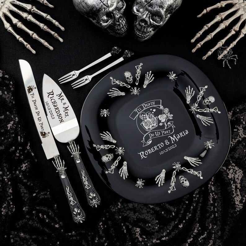 May include: A black wedding plate, cake server, and forks with a skeleton theme. The plate has the text "Til Death Do Us Part" and the names "Roberto & Maria" with the date 10/13/2023. The cake server and forks are silver.