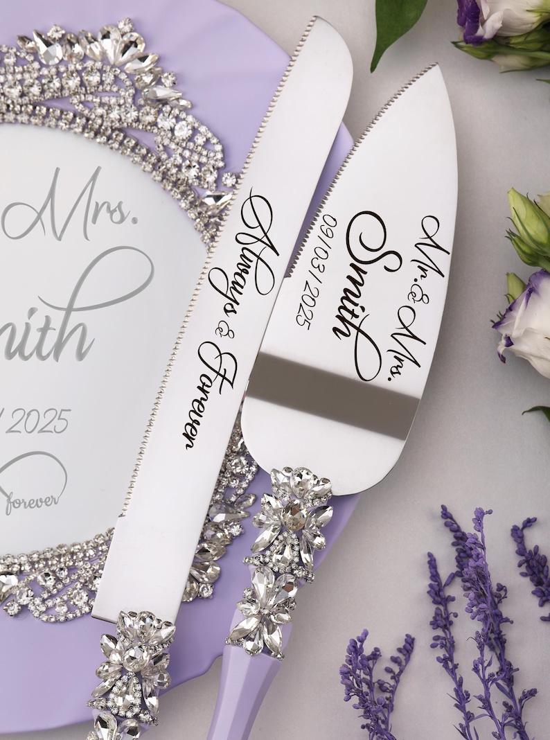 May include: A set of two silver cake cutting knives with purple handles and rhinestone embellishments. The knives are engraved with the text "Mr. & Mrs. Smith 09/03/2025" and "Always & Forever".