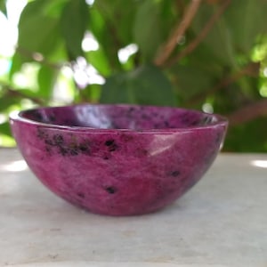 May include: A small, pink and black speckled bowl made of polished stone.